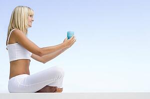 Woman sitting and meditating outdoors while holding a candle