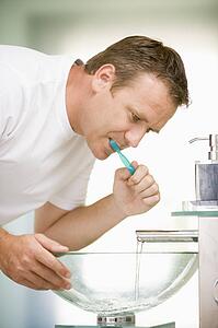 Man in bathroom brushing teeth