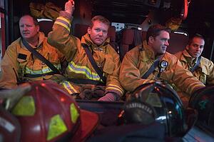 Four firemen in fire engine with gear