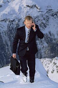 Businessman outdoors on snowy mountain using cellular phone