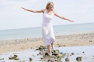 Woman walking on beach path smiling