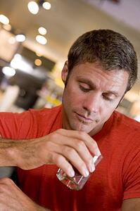 Man holding and looking into cocktail glass