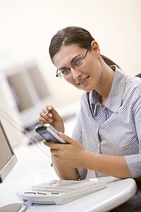 Woman in computer room using personal digital assistant and smiling