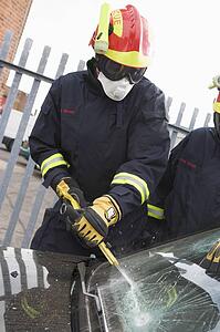 Two firefighters cutting out a windshield after an accident