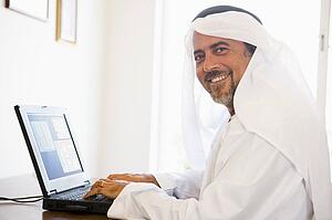 Man in office with laptop smiling (high key/selective focus)