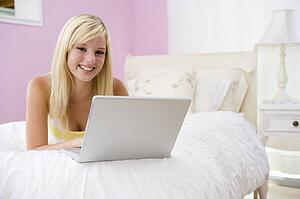Teenage Girl Lying On Bed Using Laptop 