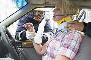 Two firemen helping a woman in neck brace breathe with oxygen mask