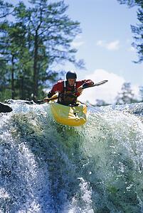 Kayaker in rapids coming over waterfall (selective focus)