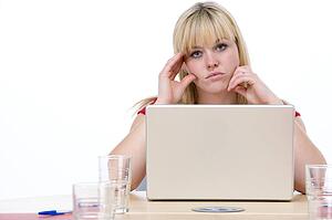 Businesswoman sitting in boardroom with laptop looking unhappy