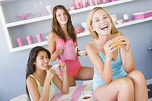 Three young woman sitting at a table having tea and a snack