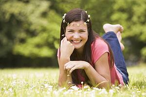 Woman lying outdoors with flowers smiling