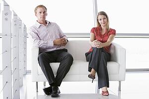 Two businesspeople sitting in office lobby smiling