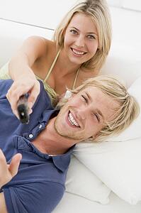 Couple in living room with remote control smiling