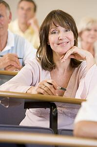 Woman sitting in adult classroom with students in background (selective focus)