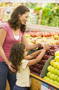Woman and daughter shopping for apples at a grocery store