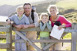 Family on cliffside path leaning on fence and smiling
