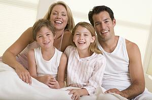 Family sitting in bed smiling