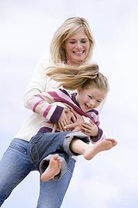 Mother and daughter playing on beach smiling