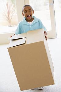 Young boy holding box in new home smiling