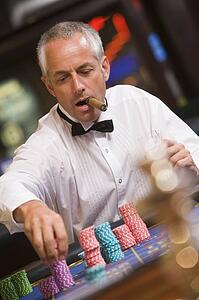 Man in casino playing roulette and smoking cigar (selective focus)