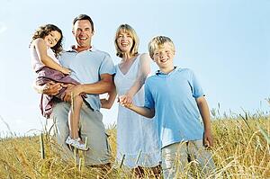 Family standing outdoors holding hands smiling