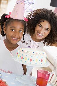 Mother and daughter with birthday cake smiling
