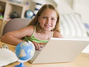 Young Girl Doing Homework On A Laptop