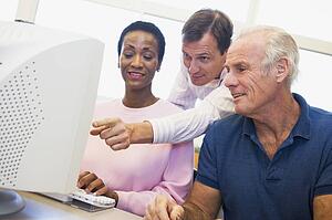 Three people at a computer terminal (depth of field/high key)