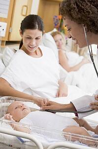 Doctor checking baby's heartbeat with new mother watching and smiling