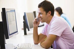 Man in computer room using cellular phone and smiling