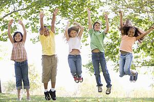 Five young friends jumping outdoors smiling