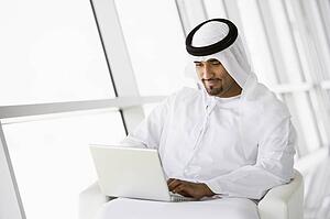 Man indoors with laptop smiling (high key/selective focus)