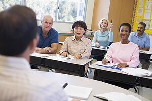 Adult students in class with teacher (selective focus)