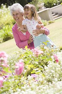 Grandmother and granddaughter outdoors in garden smiling