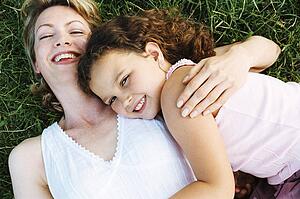 Mother and daughter lying outdoors smiling