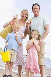 Family standing at beach with ice cream smiling