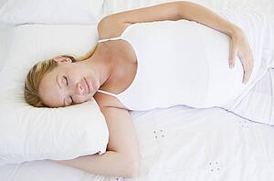 Pregnant woman lying in bed sleeping