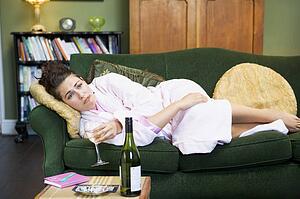 Young woman lying on sofa smoking and drinking wine