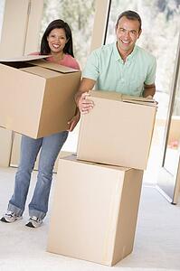 Couple with boxes moving into new home smiling