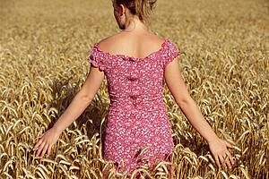 Woman standing outdoors in wheat field (selective focus)