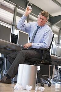 Businessman in office space throwing garbage in bin