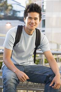 Man sitting on bench outdoors smiling (selective focus)