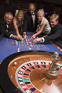 Group of people in casino playing roulette and smiling (selective focus)