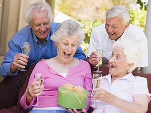 Two couples on patio with champagne and gift smiling