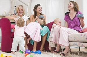 Three mothers in living room with coffee and babies smiling