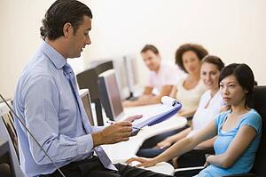 Man with clipboard giving lecture in computer class