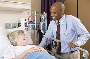 Doctor Talking To Senior Woman Lying In Hospital Bed