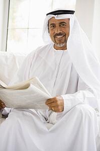 Man sitting indoors with newspaper smiling (high key/selective focus)