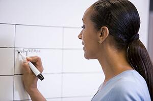Businesswoman indoors writing on erasable board