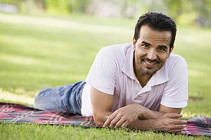 Man lying outdoors at park smiling (selective focus)